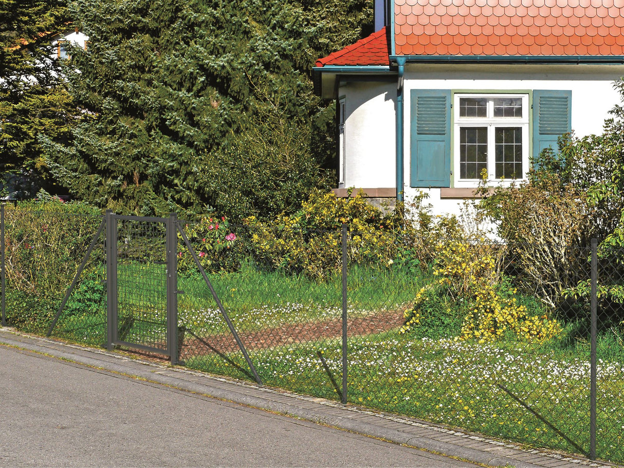 Ein Maschendrahtzaun mit Tor in anthrazit, der vor einem Haus und dessen Garten steht. 