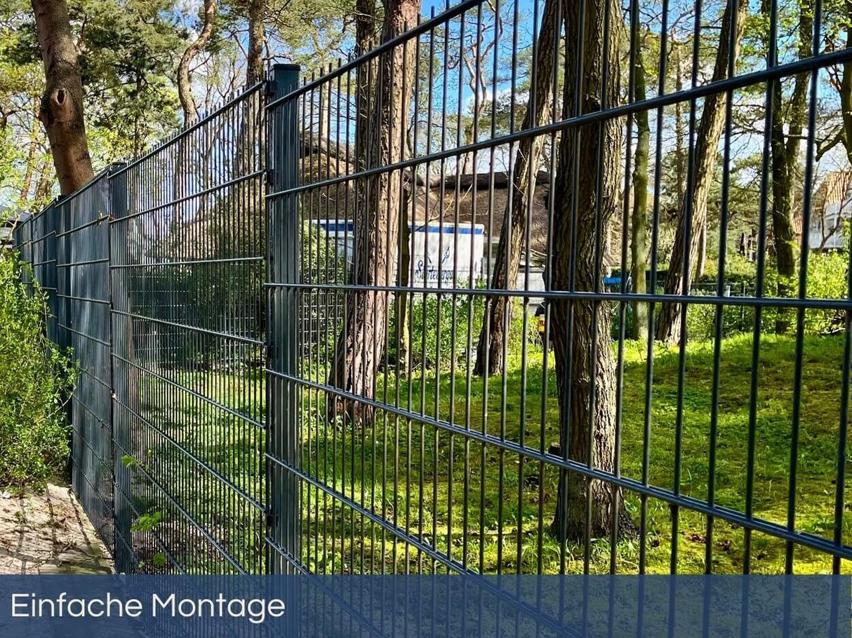 Hoher Sicht- und Sicherheitsschutz durch einen 183 cm hohen Doppelstabmattenzaun in Anthrazit vor einer natürlichen Baumkulisse.